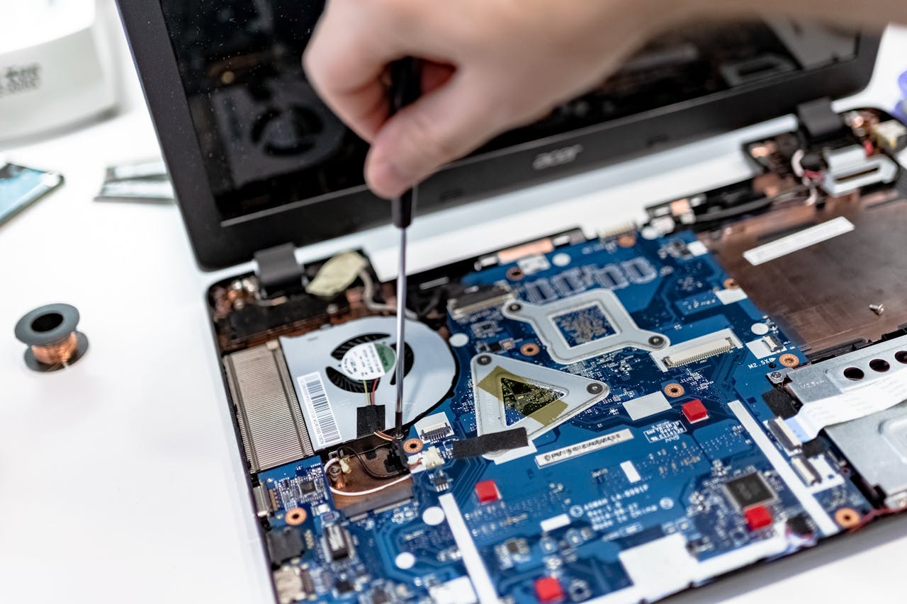 services-03 Hand repairing a laptop motherboard with a screwdriver, highlighting tech maintenance.
